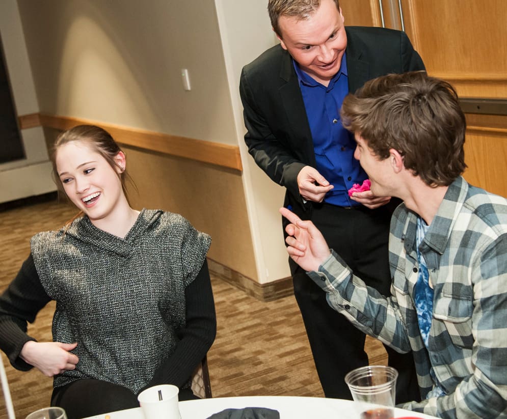 David Farr performing a magic trick for laughing teens